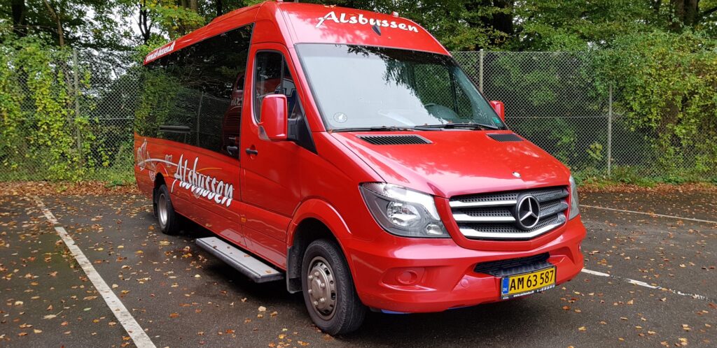 Rød minibus med teksten Alsbussen parkeret udendørs